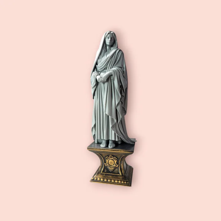 Estátua em resina cinza de figura feminina velada, com as mãos recolhidas à frente, sobre pedestal dourado ornamentado