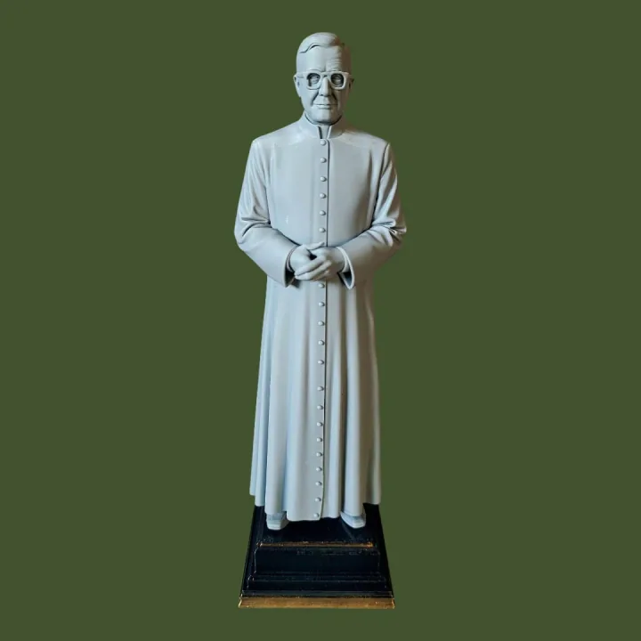 Estátua impressa em 3D de São Josemaria Escrivá em batina, de óculos e mãos unidas, em resina clara sobre base preta e dourada